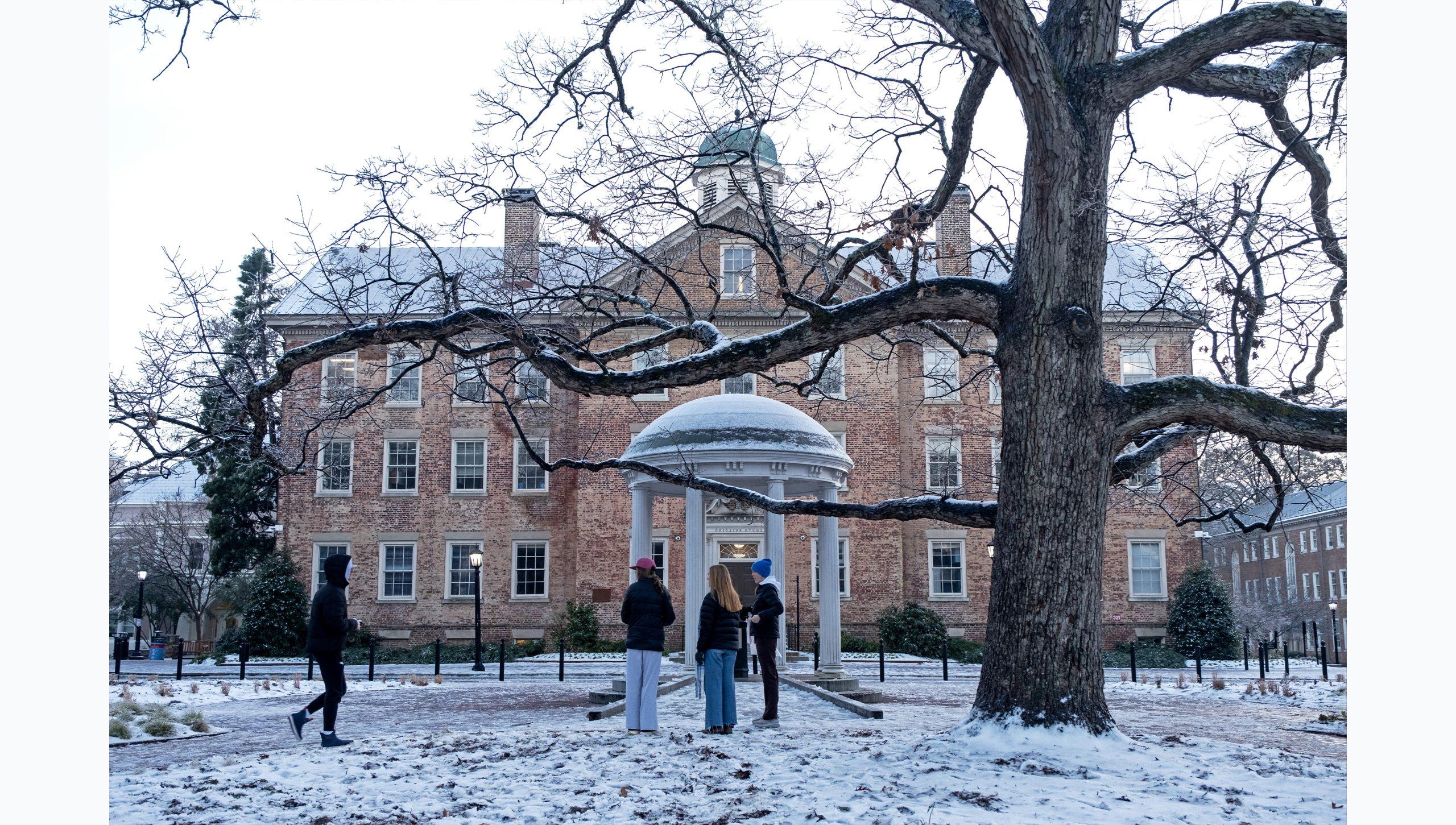 Students hanging out by the Old Well on a snowy day on the campus of U.N.C Chapel Hill.